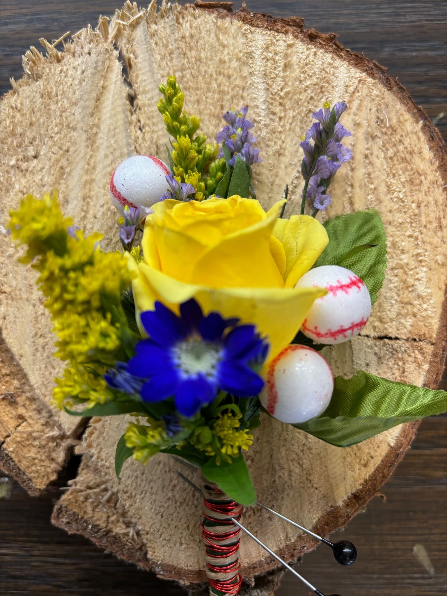 a white rose with green leaves is on a wooden table