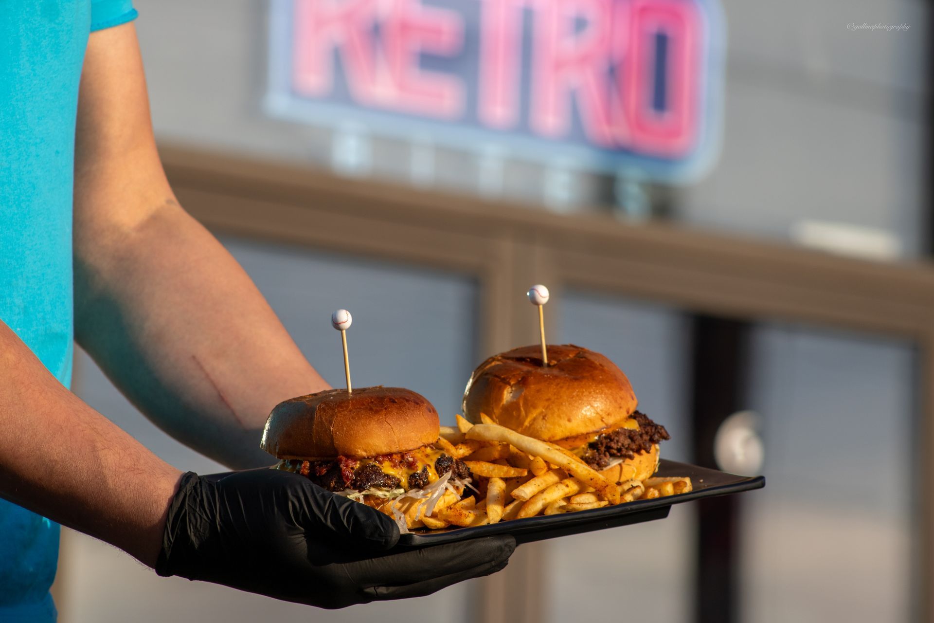 A person is holding a tray of hamburgers and french fries.