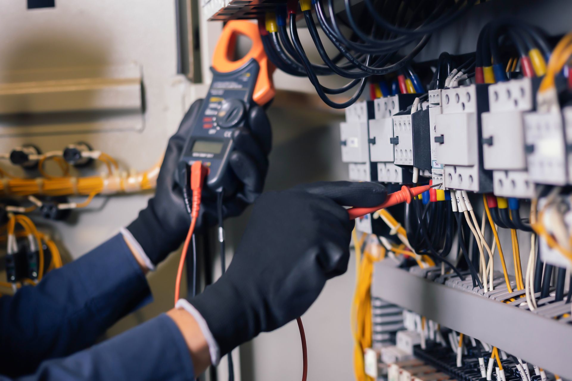 Technician using a multimeter to test wiring in an electrical control panel
