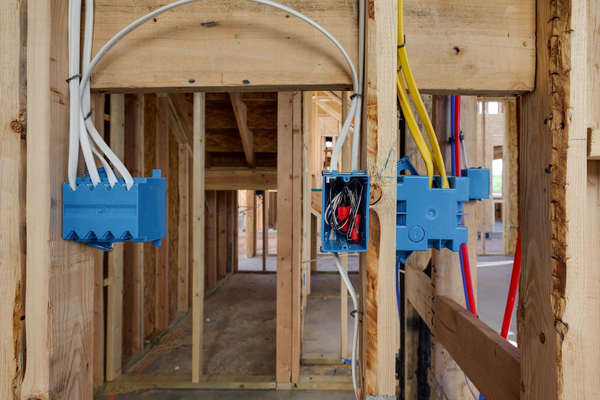 Framed house interior with electrical wiring boxes and conduits in unfinished walls