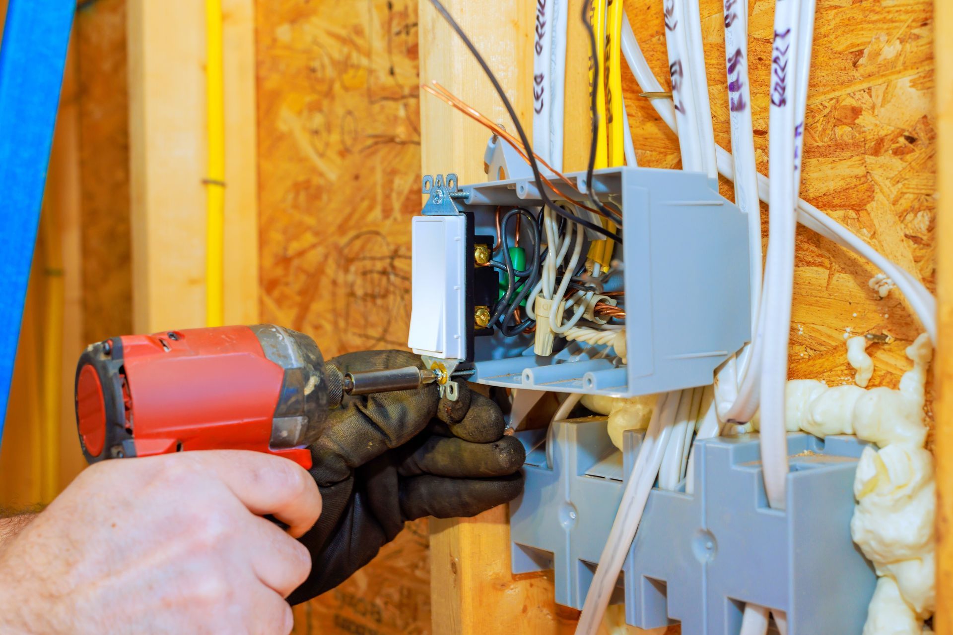Electrician using a drill to install wiring in an open wall junction box
