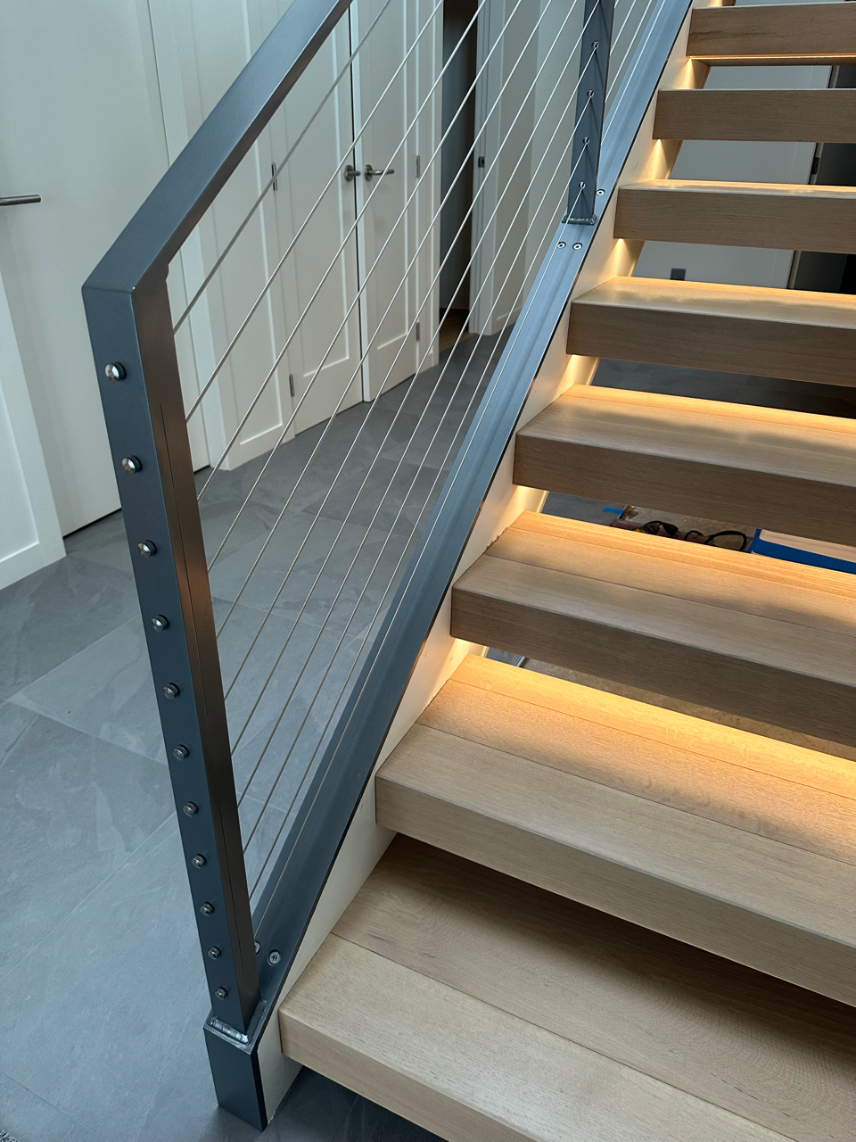 A wooden staircase with a metal railing and lights on the steps