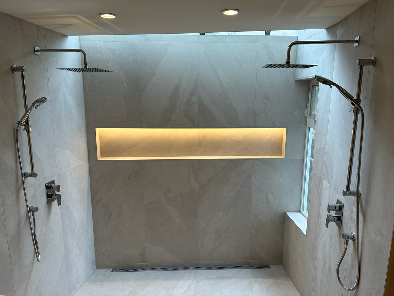 A bathroom with two showers and a window