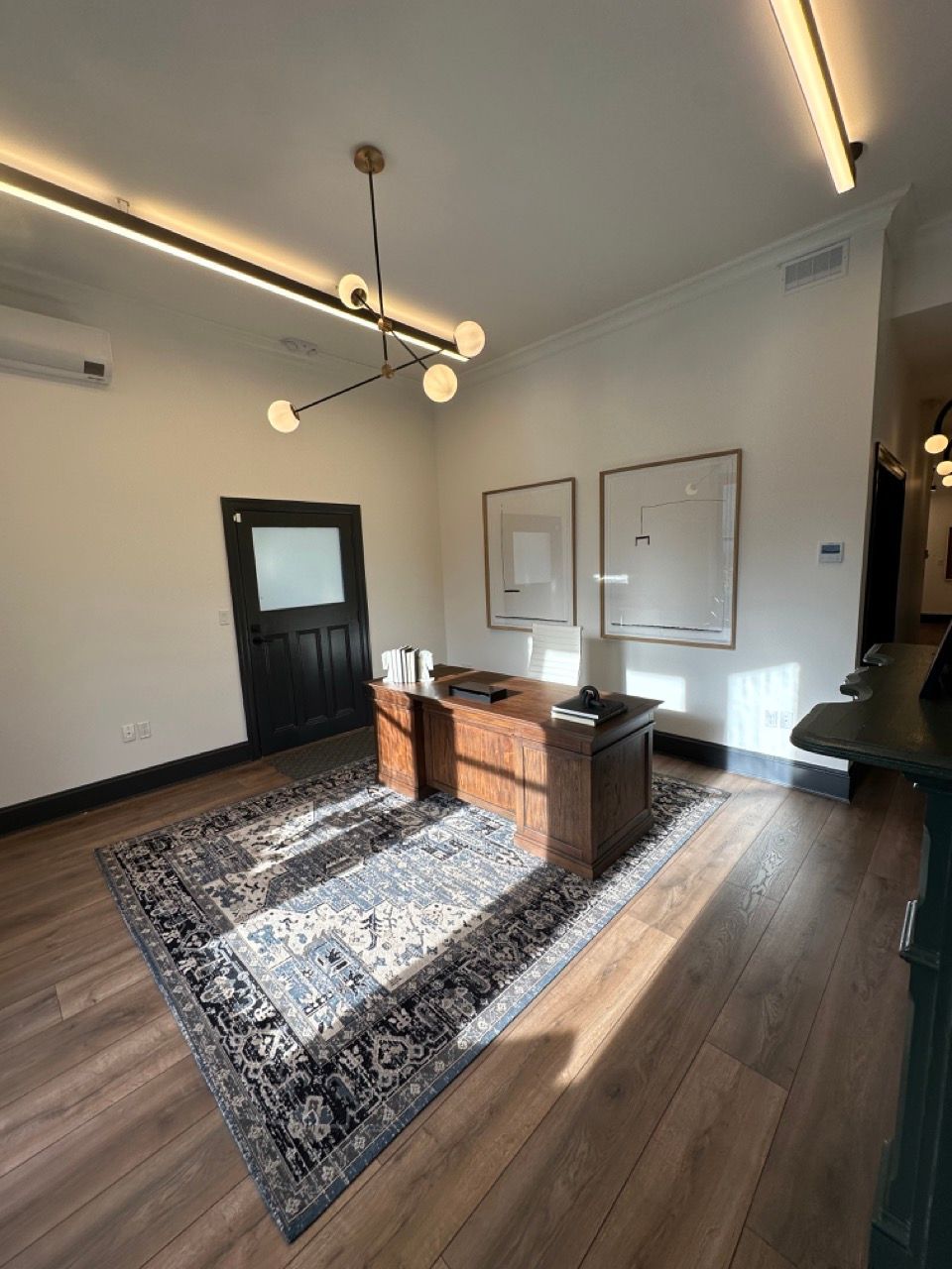 A room with a desk and a rug on the floor