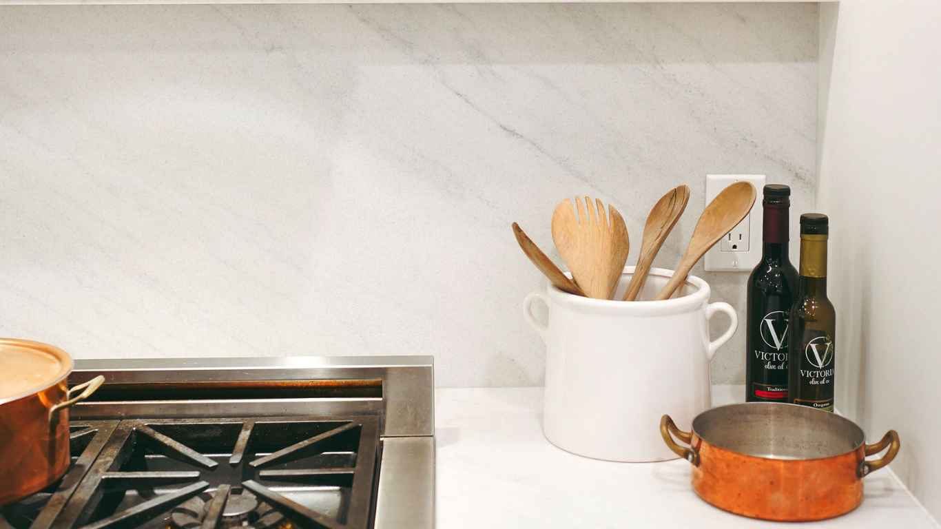 A kitchen counter with pots , pans , and utensils on it.