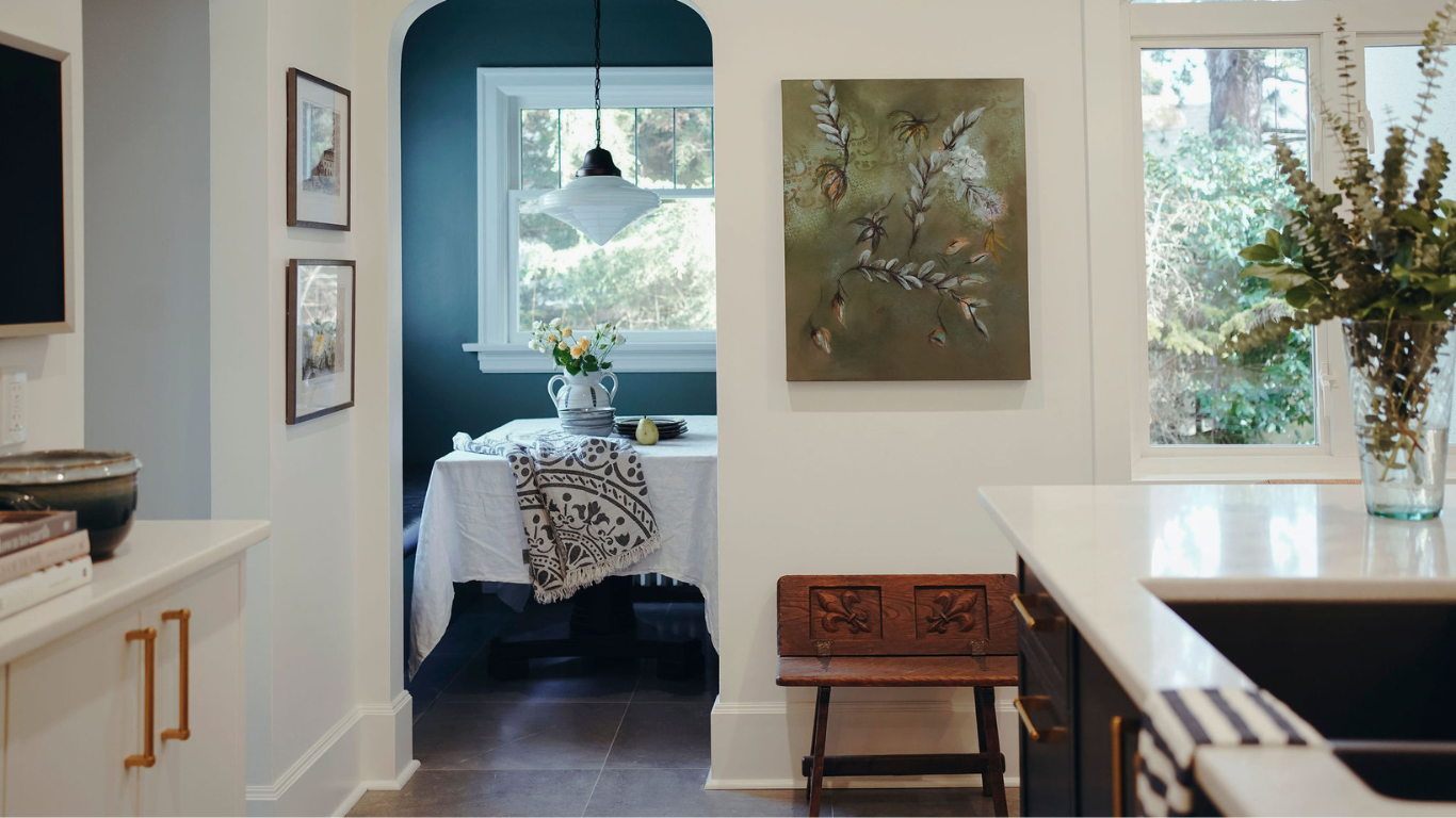 A kitchen with a table and chairs and a painting on the wall.