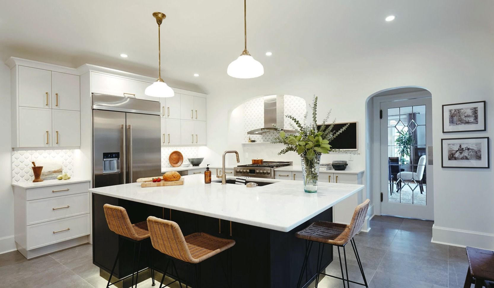 A kitchen with white cabinets , stainless steel appliances and a large island.