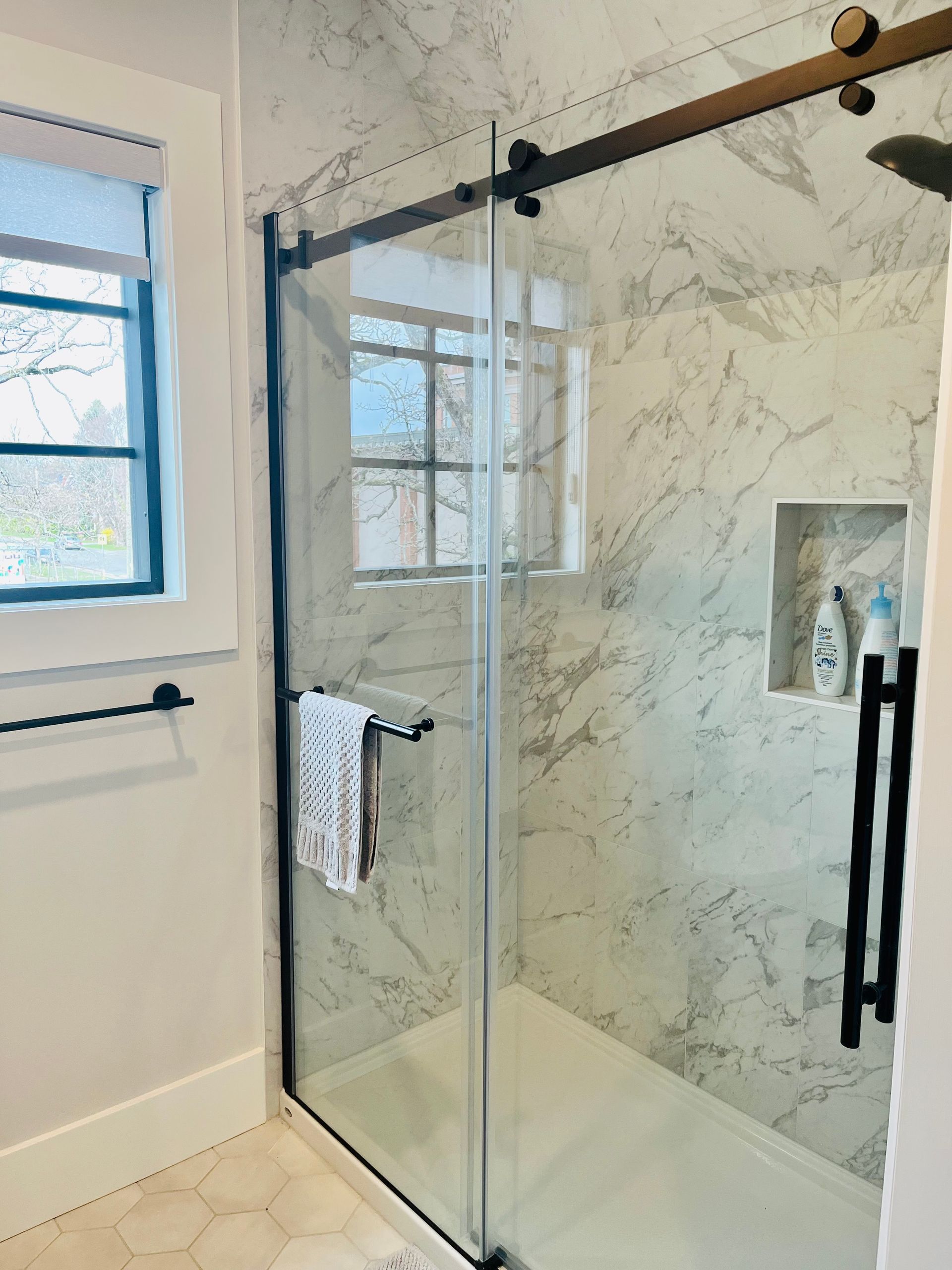 A bathroom with a sliding glass shower door and a window.