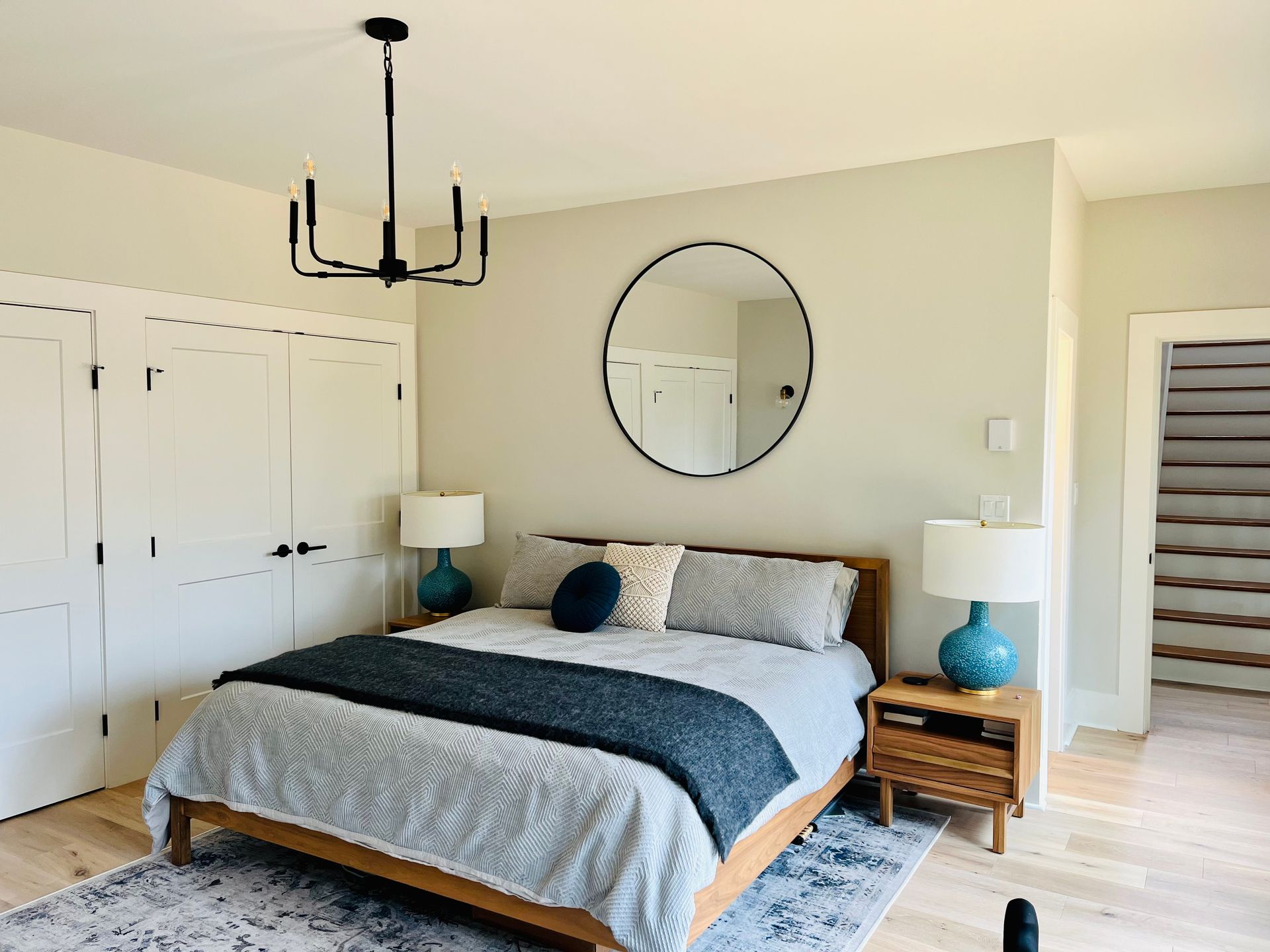 A bedroom with a bed , lamps , a mirror and a chandelier.
