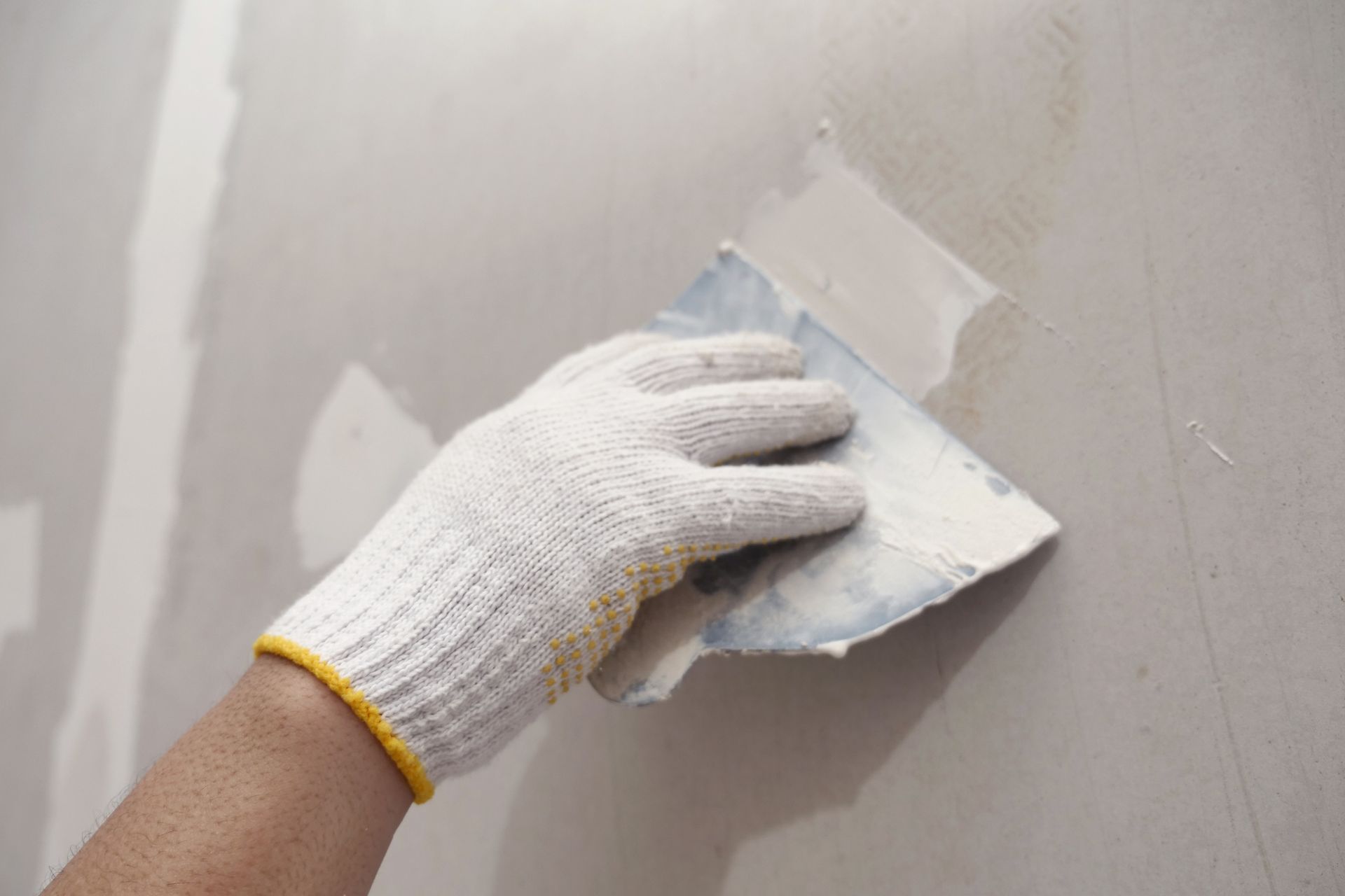 A person is plastering a wall with a spatula.