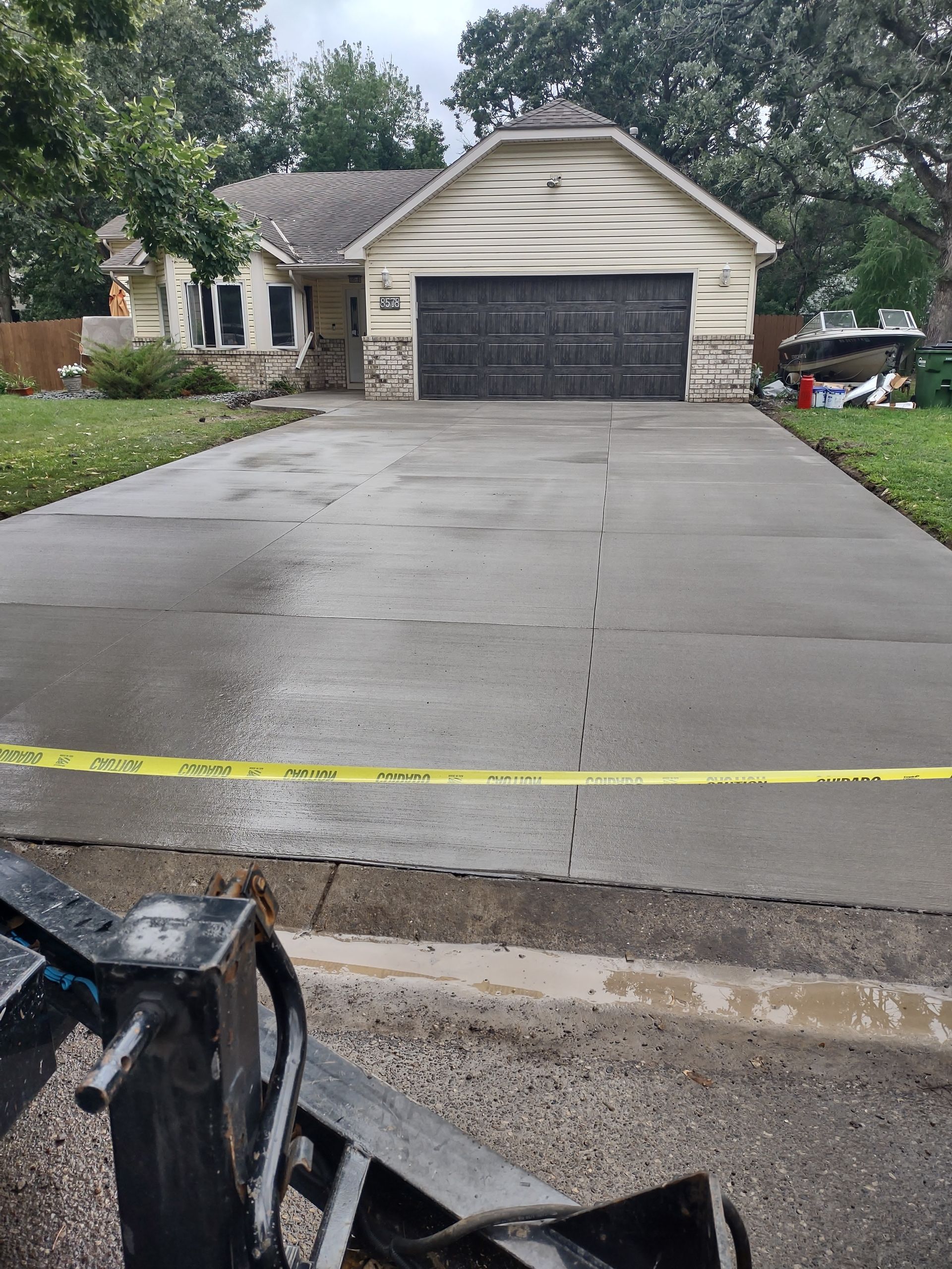 A concrete driveway is being installed in front of a house.