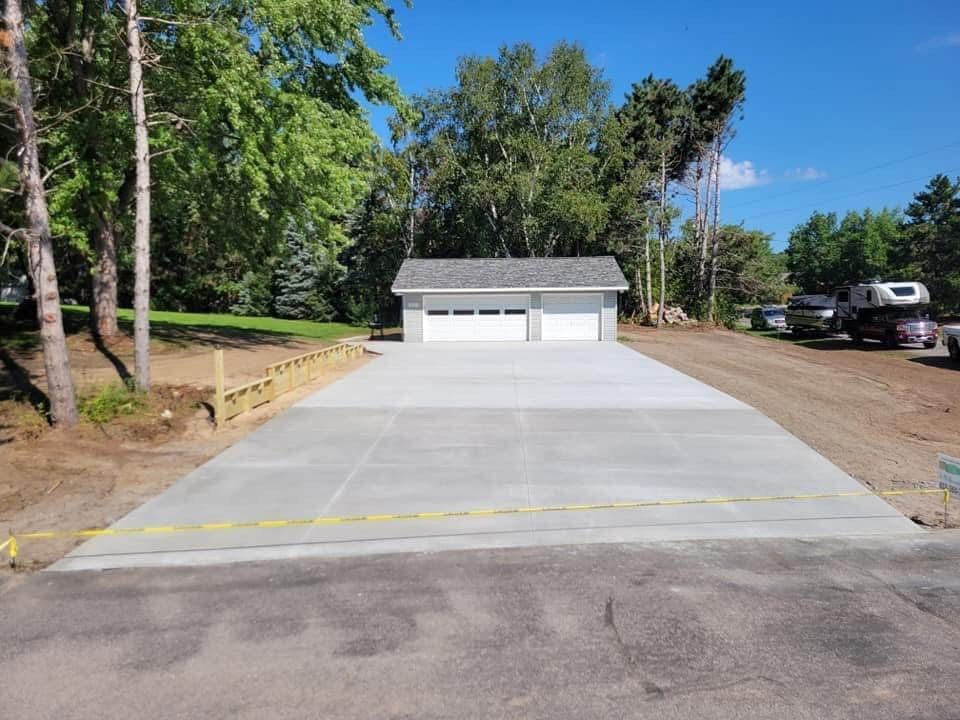 A concrete driveway with a garage in the background