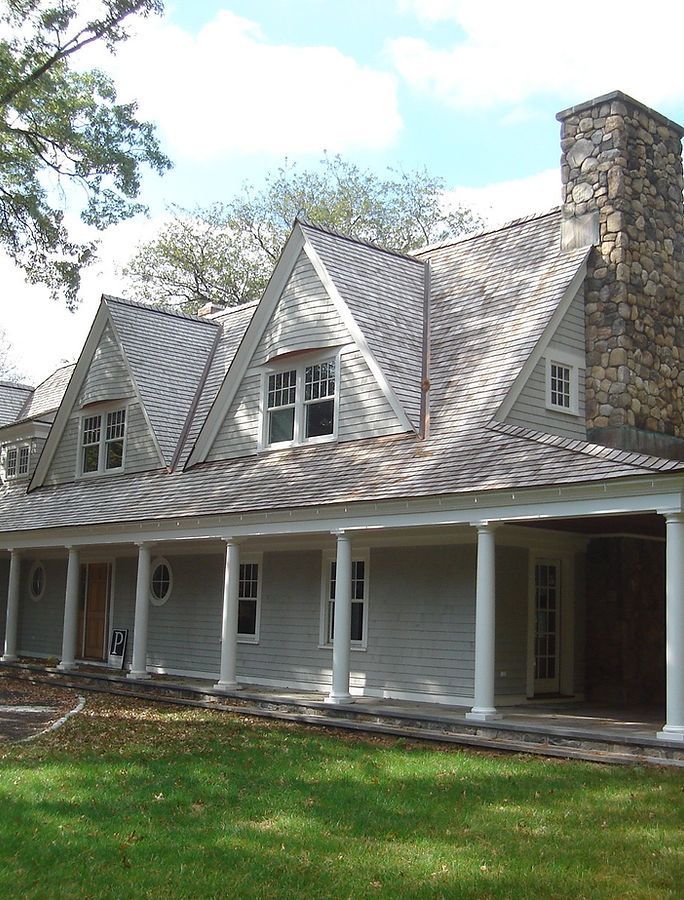 Gray house with gabled roof and large stone chimney, featuring a covered porch.