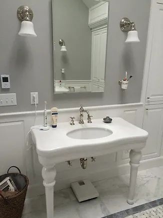 Bathroom with white sink, mirror, and fixtures against gray walls; toothbrush and shaver on counter.