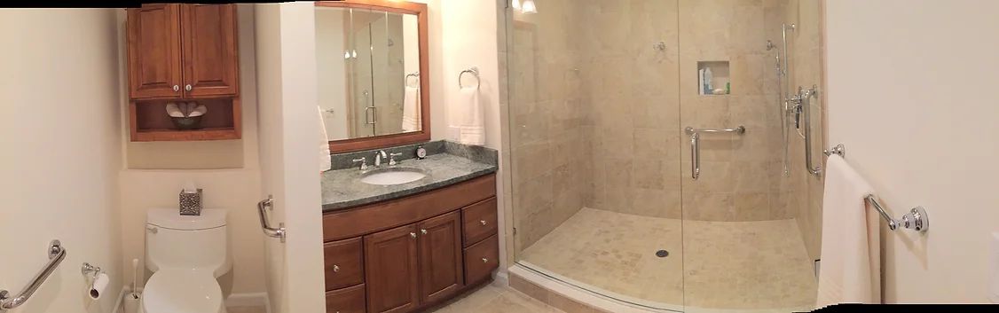 Bathroom with a toilet, vanity, and large walk-in shower. Brown cabinets, stone-like shower walls.