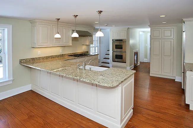 Kitchen with light-colored cabinets, granite countertops, and hardwood floors. Features an island and built-in appliances.