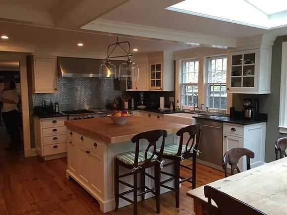 Spacious kitchen with wood island and countertops, white cabinets, stainless steel appliances, and wooden floors.