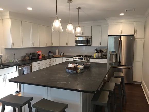 White kitchen with island, stainless steel appliances, and dark countertops.