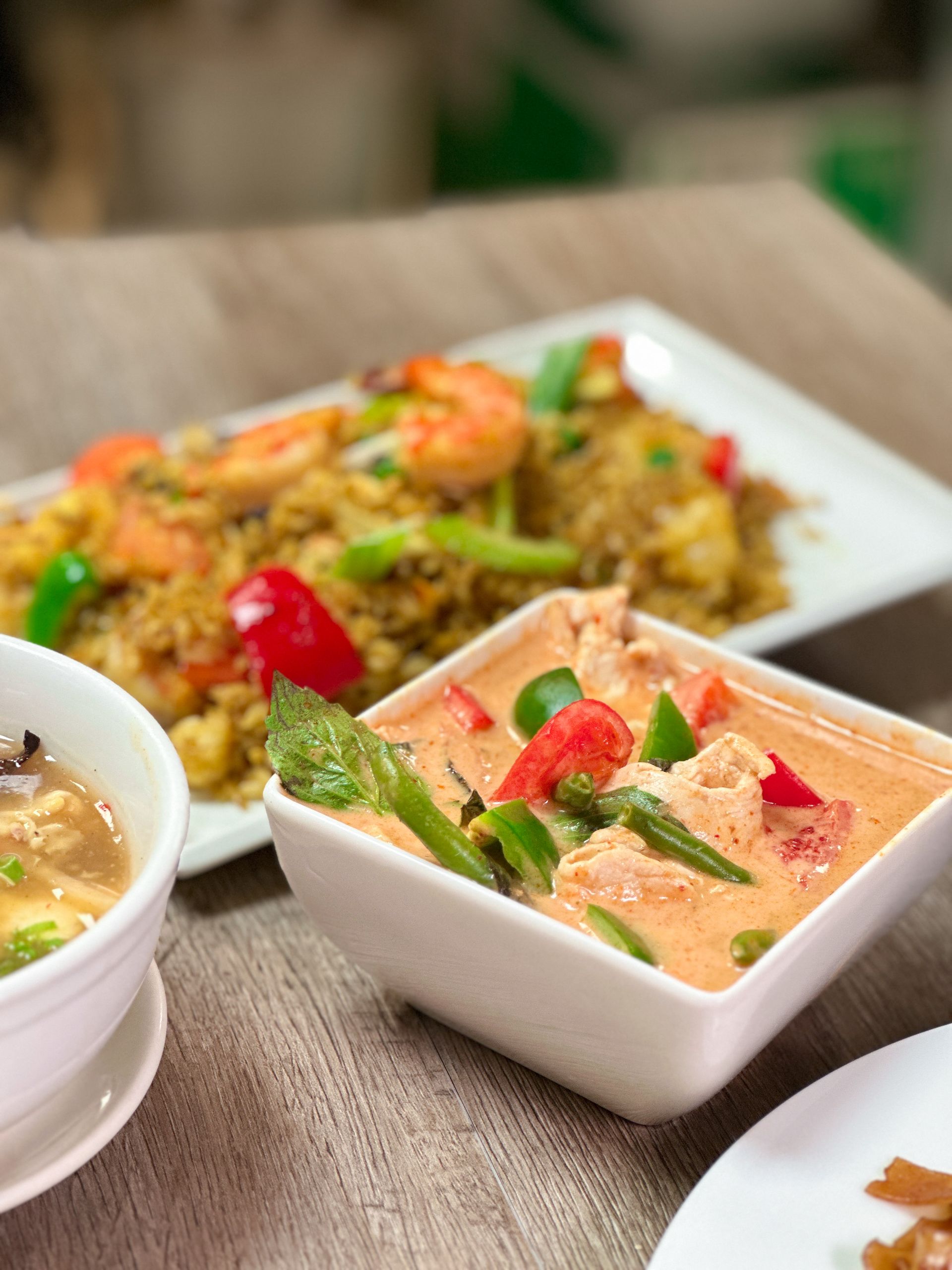 A bowl of soup next to a plate of food on a table
