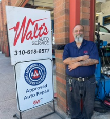 A man is standing in front of a walt 's auto service sign | Walt's Auto Service