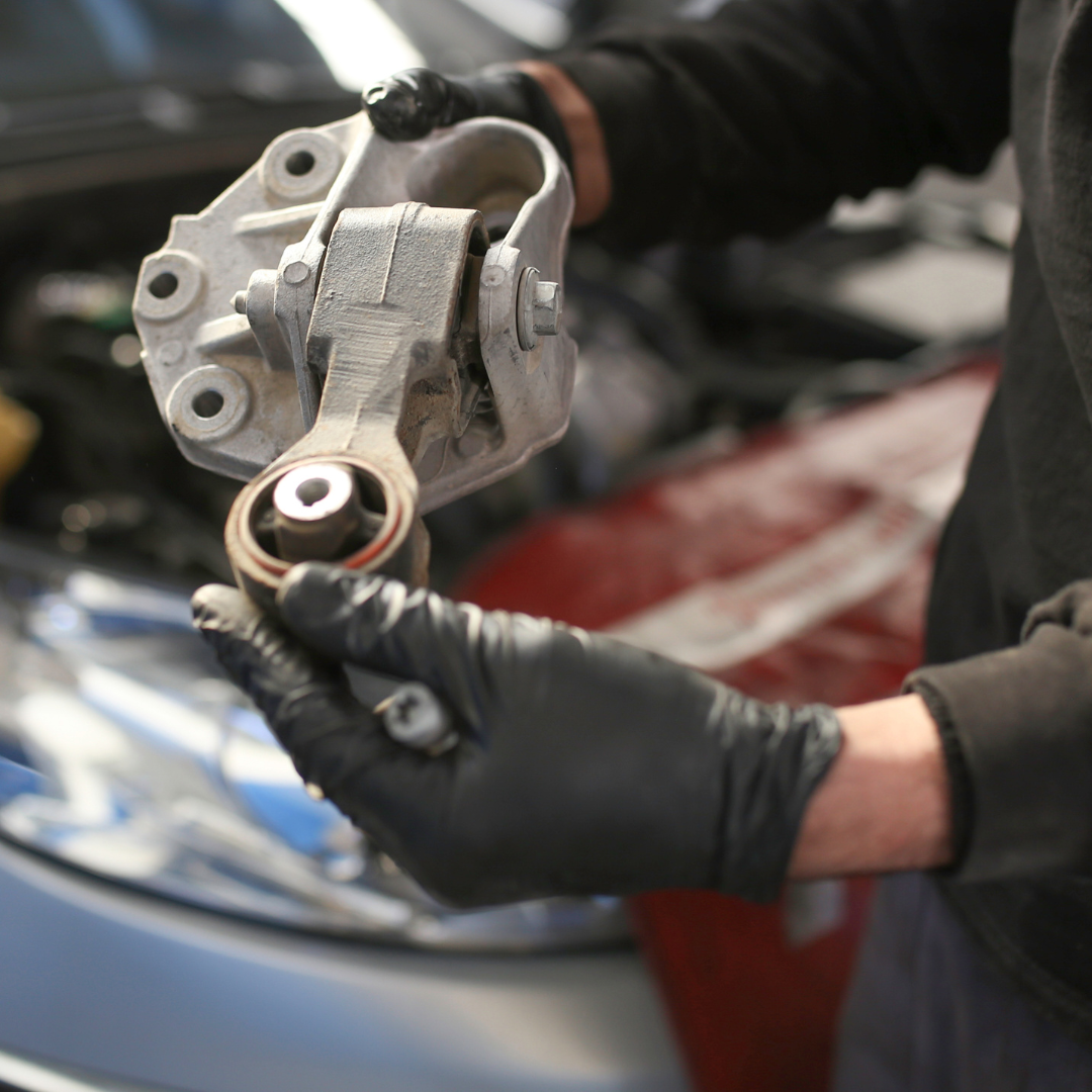 A person wearing black gloves is holding a piece of metal | Walt's Auto Service