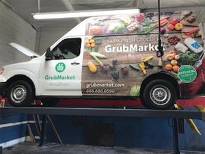 A white van is parked on a lift in a garage. | Walt's Auto Service