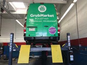 A green van is sitting on a lift in a garage. | Walt's Auto Service