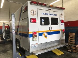 An ambulance is sitting on a lift in a garage. | Walt's Auto Service