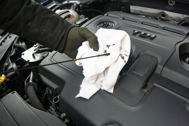 A person is checking the oil level of a car | Walt's Auto Service