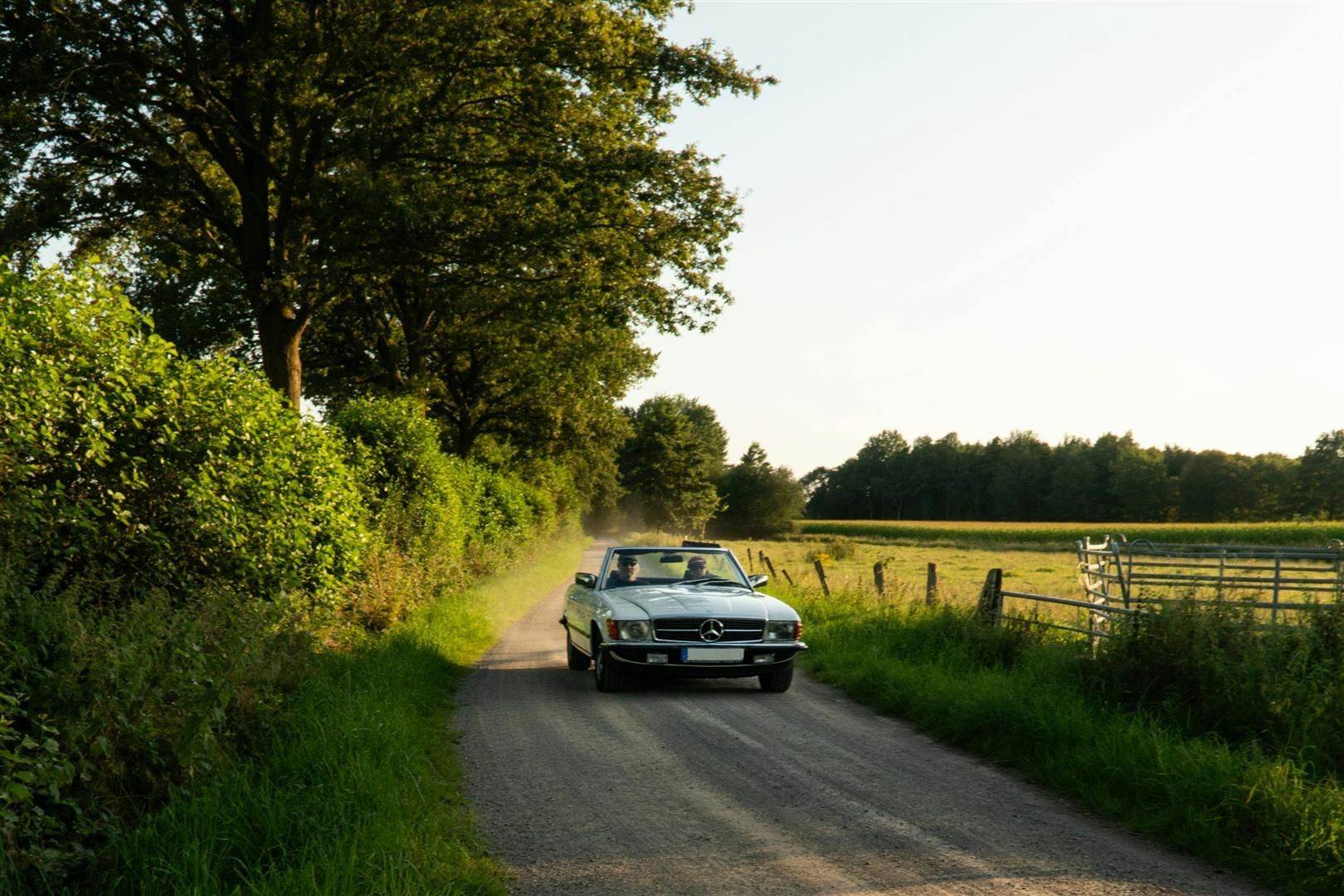 A white car is driving down a dirt road. | Walt's Auto Service