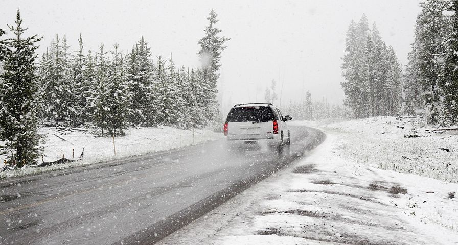 A car is driving down a snowy road. | Walt's Auto Service
