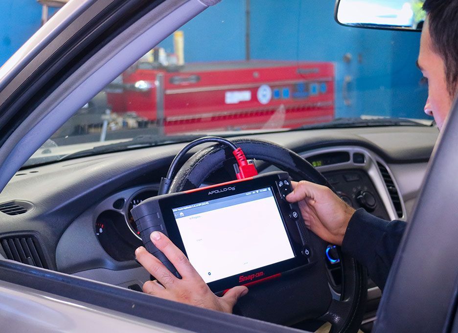 A man is sitting in a car using a tablet | Walt's Auto Service