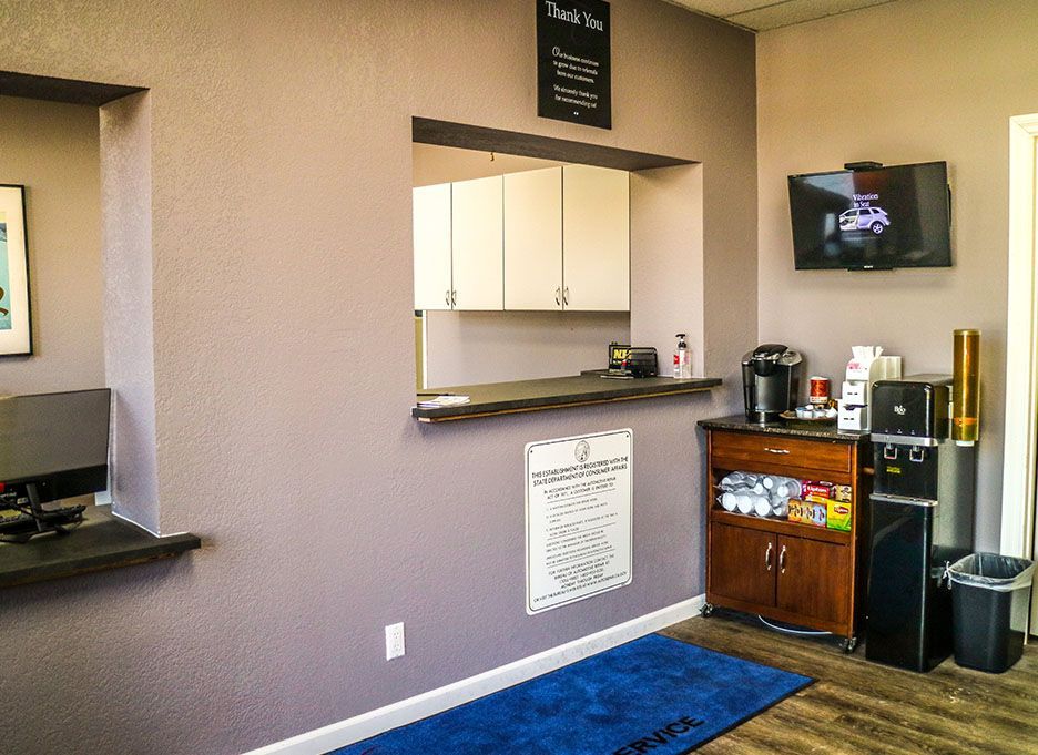 A waiting room with a counter and a television on the wall. | Walt's Auto Service