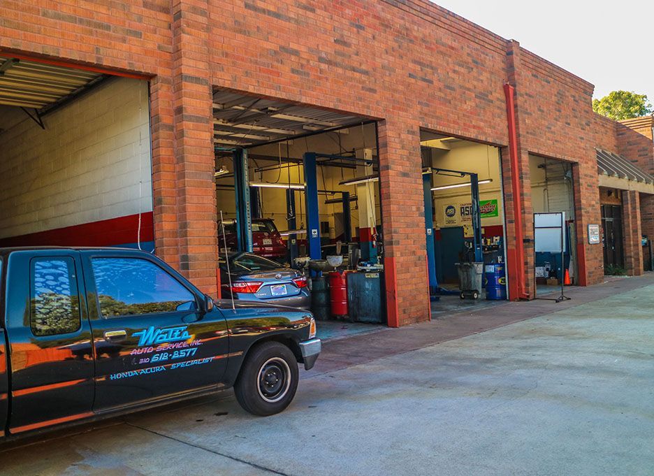 A black truck is parked in front of a brick building. | Walt's Auto Service