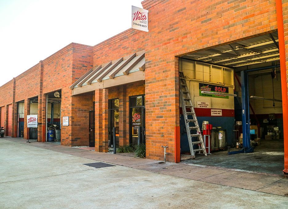 A brick building with a ladder in front of it. | Walt's Auto Service