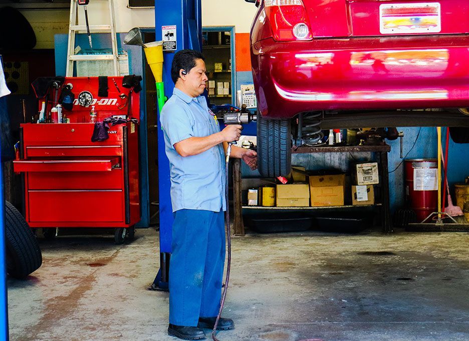 A man is working on a red car in a garage | Walt's Auto Service
