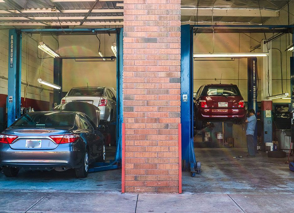 Two cars are sitting on a lift in a garage. | Walt's Auto Service