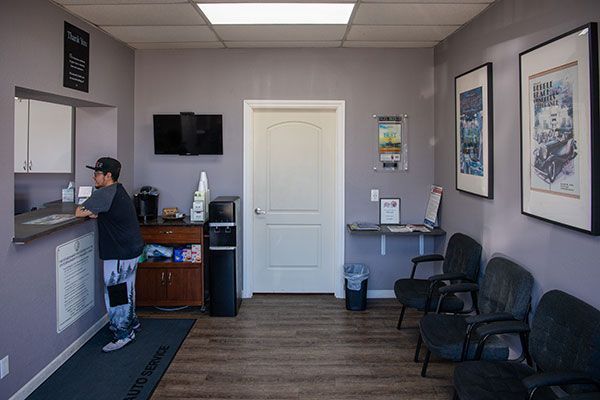 A man is standing at a counter in a waiting room. | Walt's Auto Service