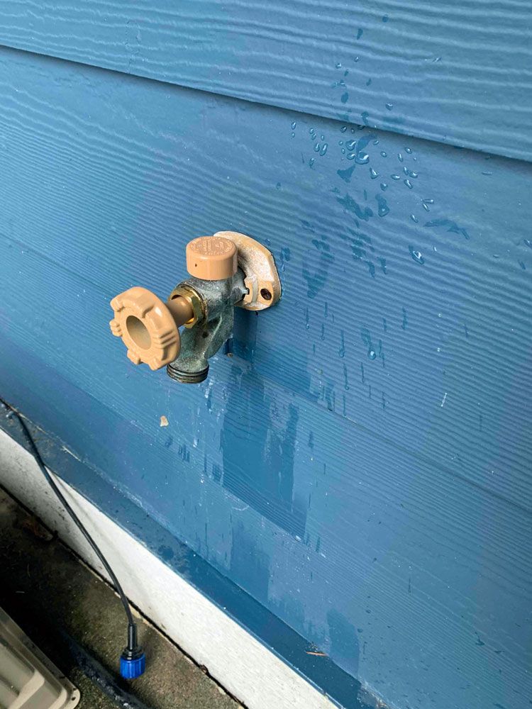 A close up of a faucet on a blue wall.