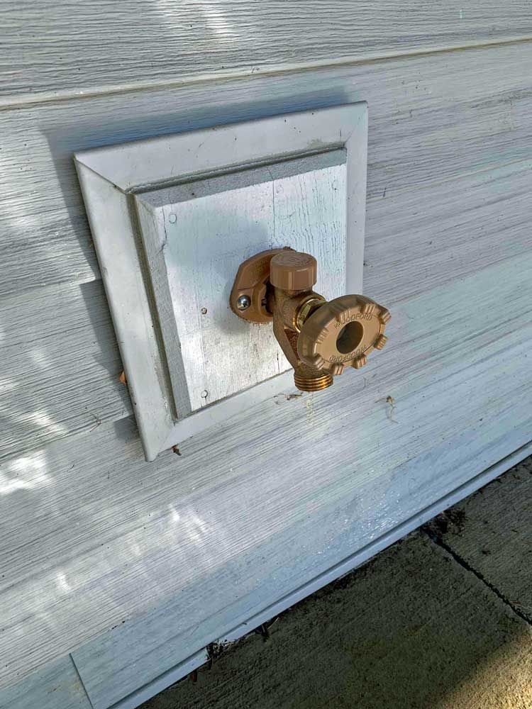 A close up of a faucet on the side of a house.