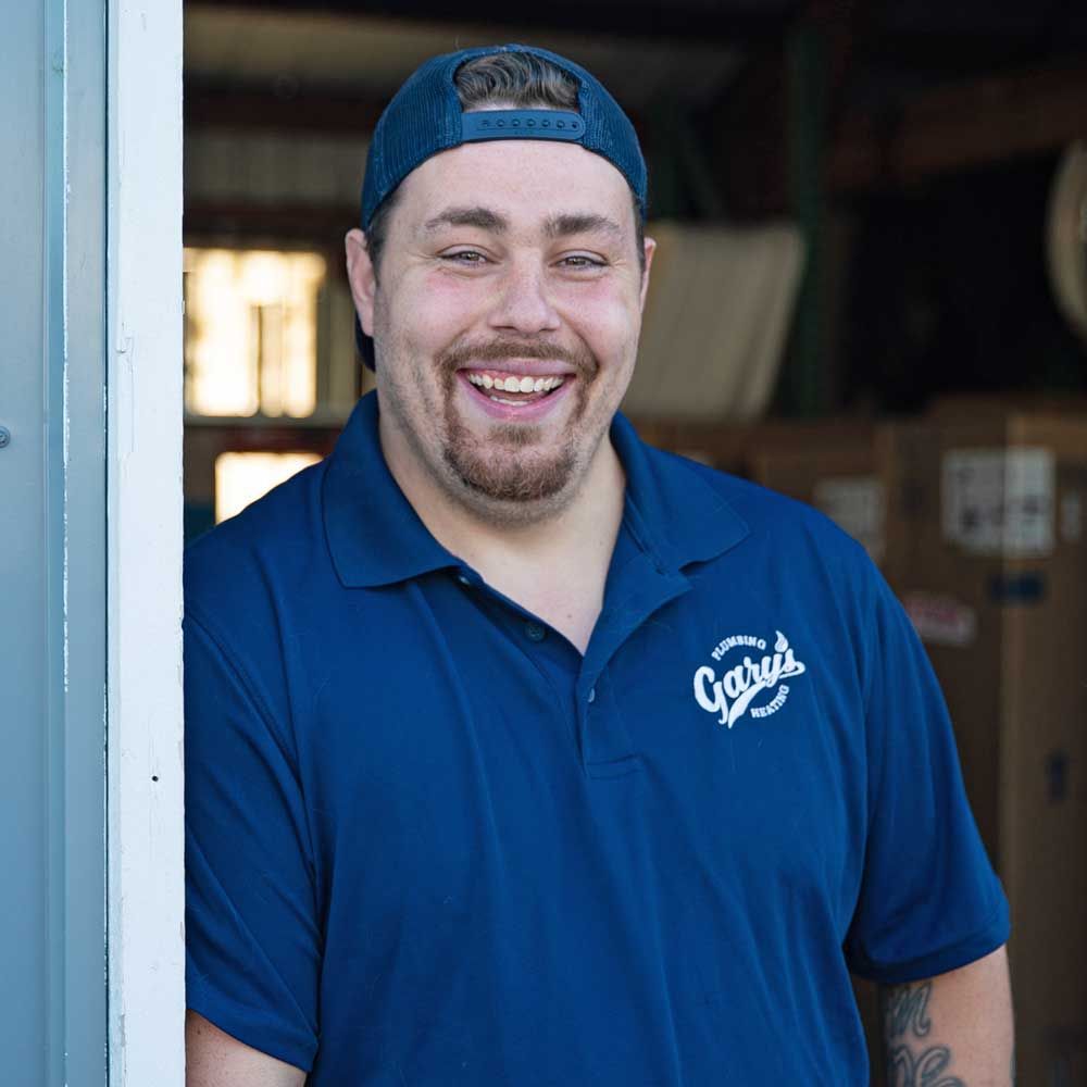 A man wearing a blue shirt and a hat is smiling