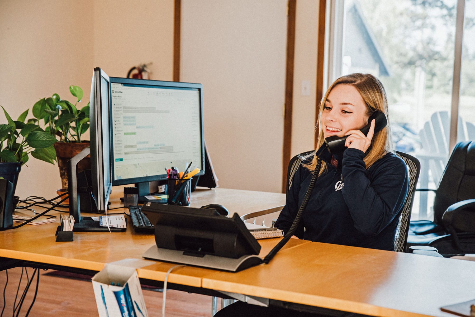 A woman is sitting at a desk talking on a phone.