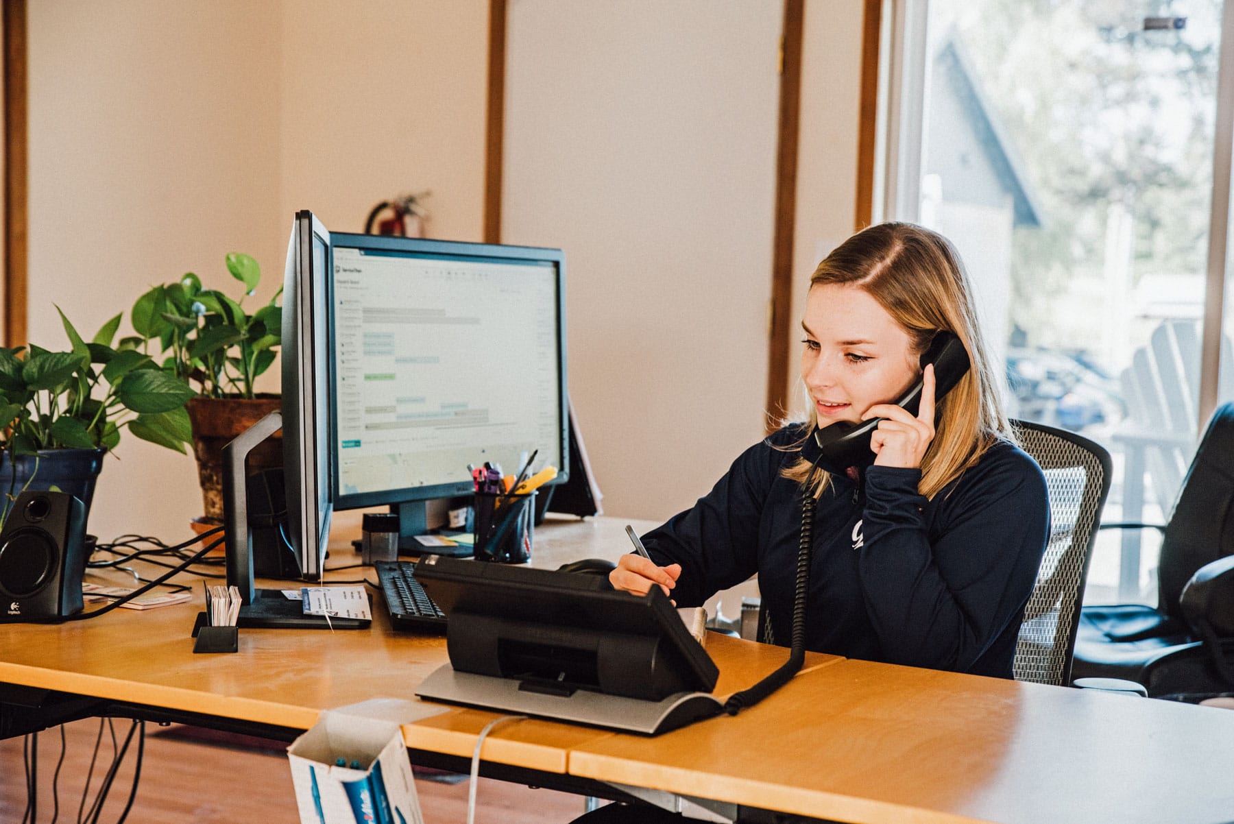 A woman is sitting at a desk talking on a phone.