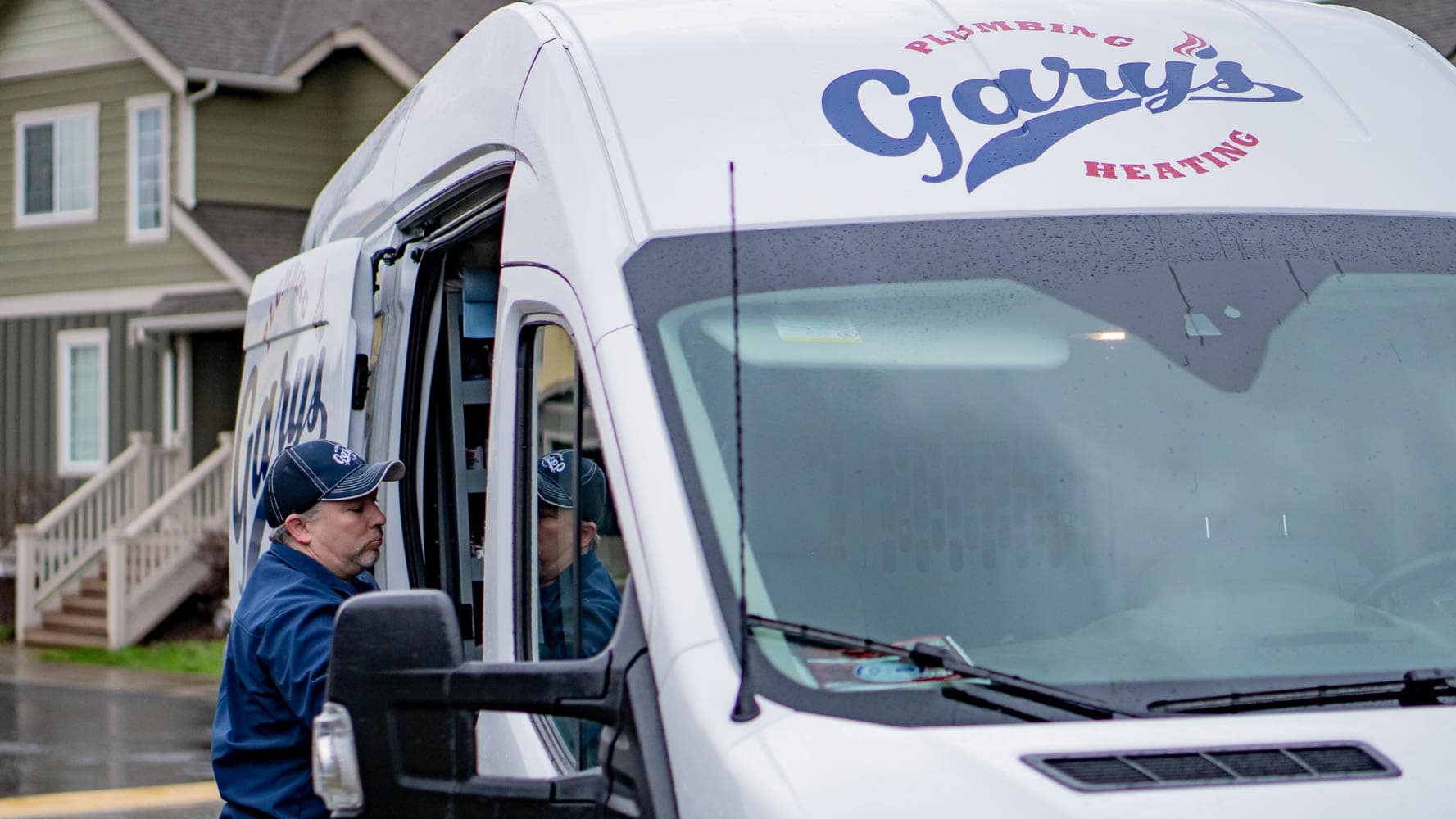 A man is getting out of a Gary 's  van.