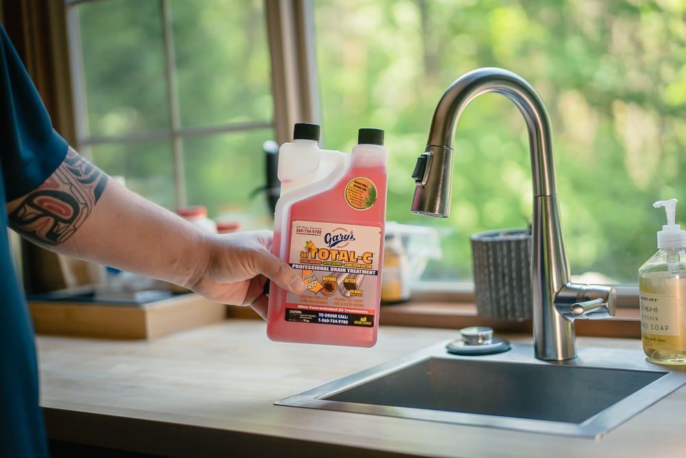 A person is holding a bottle of cleaner in front of a sink.
