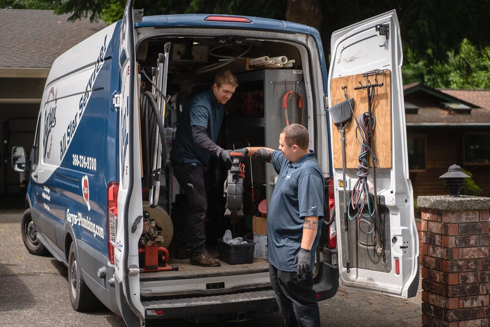 Two men are standing in front of a van.