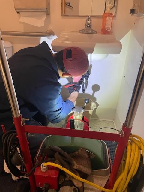 A man is working on a sink in a bathroom.
