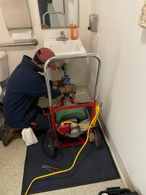 A plumber is working on a sink in a bathroom