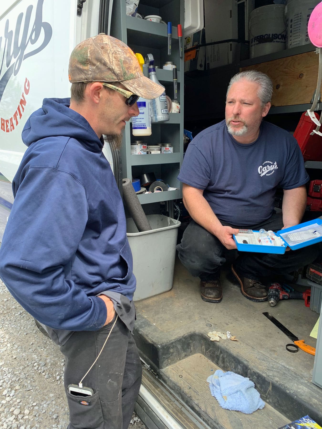 Two men are standing next to each other in front of a van.