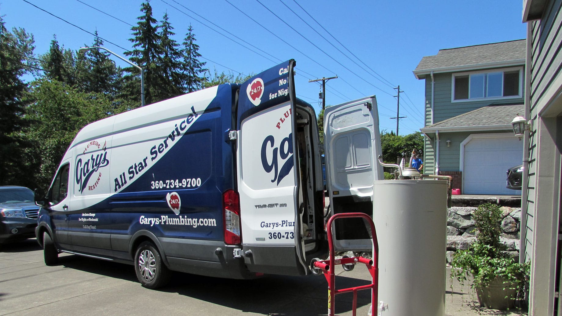 A blue and white van is parked in front of a house.